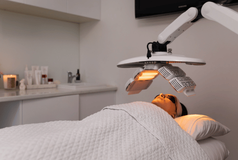woman laying on treatment bed with an LED lamp above her